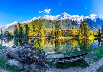 The bench in the city park. Chamonix City Park is illuminated by sunset. The lake reflects the  French Alps, the forest and the blue sky. Concept of active winter tourism