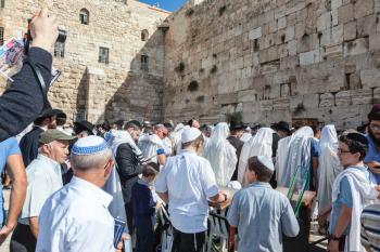 JERUSALEM, ISRAEL - OCTOBER 12, 2014:  Morning autumn Sukkot. The area in front of Western Wall of  Temple filled with people. Crowd of Jewish worshipers in white wearing prayer shawls