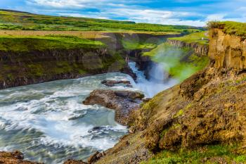 Tundra on a sunny summer day. The waterfall in Iceland - Gullfoss on the Hvitau River. Huge masses of water crash into a narrow gorge. The concept of extreme and phototourism