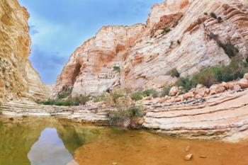 Picturesque canyon Ein-Avdat in the Negev desert. Clean cold water in the creek canyon. Sandstone walls apart, like butterfly wings