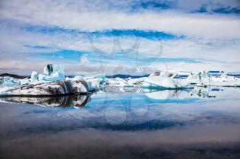 Icebergs and ice floes are reflected in the mirrored water of the ocean Bay. Summer vacation in Iceland. Ice lagoon in July