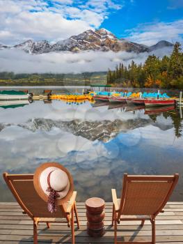 Concept of  vacation and tourism. Two deck chairs on a wooden platform. Boat station waiting for tourists. Pyramid Mountain, Jasper National Park
