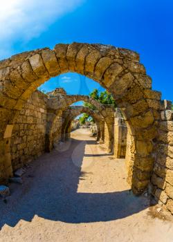  Excursion to the Archaeological Park of the Roman Empire in ancient Caesarea. Sunny spring day. Israel. Concept of ecological and historical tourism. The remains of the covered arcades