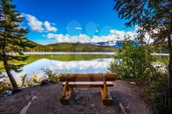 On the shore of lake - comfortable wooden benches. Early morning on cold Pyramid Lake, Jasper National Park