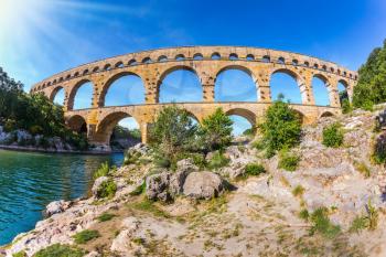 Three-tiered aqueduct bridge Pont du Gard was built in Roman times on the river Gardon. Provence sunset. Photo taken fisheye lens