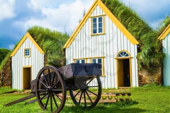 The ancient two-wheeled wooden cart on the front lawn. The village first settlers in Iceland. The reconstituted village - Pioneer Museum - Viking