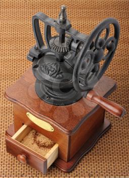 Antique hand-mill for coffee on a wicker mat.