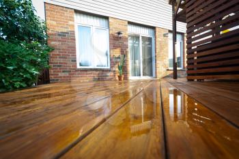 Backyard wooden deck floor boards with fresh brown stain, angled view