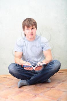 relaxed man sitting on the floor with book
