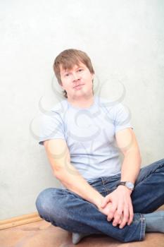 relaxed man sitting on the floor against wall