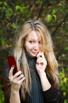 Young cute girl with long blond hairs with cell phone. Fall. Autumn. Outdoor session.
