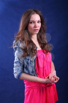 Fashion girl posing in pink dress on blue background
