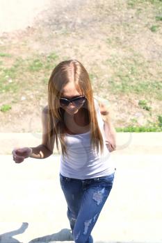 Blond woman in jeans and dark glasses standing on an outdoor summer patio