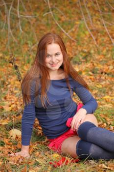 Redhead Woman sitting in the park in autumn