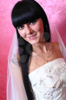 closeup portrait of a happy beautiful brunette bride against red background