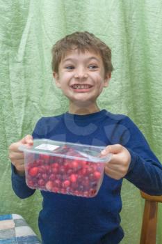 Kid smiling face portrait with pack of cherries.
