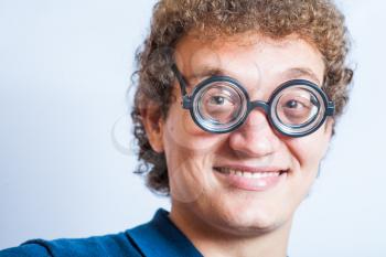 Closeup fun headshot of curly hair man smiling. Portrait of a man with nerd glasses n studio funny