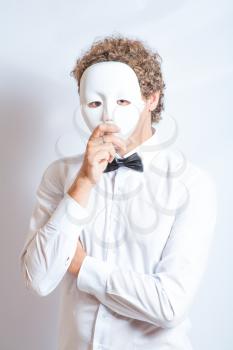 Vertical shot of mime close-up in white shirt and black bow tie, theatrical white mask on the face