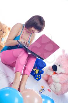 Young girl using a laptop near bear toys on white