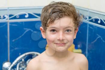Smiling little boy in bathroom against a blue wall head and shoulders shot