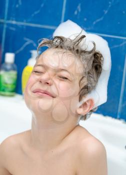 boy in soap bubbles in the bathroom very happy