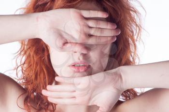 Redhead covering her face with hands on white