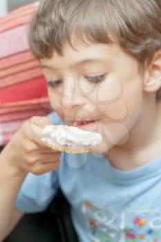 Cute little boy eating chocolate ice cream indoors