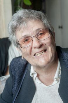 Closeup portrait of senior woman with glasses, looking at camera, smiling.