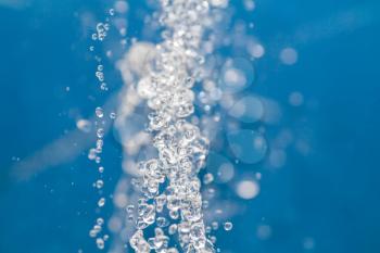 Abstract macro photo of water drops falling down against blue backgrouns. Backgrouns for spa health concept