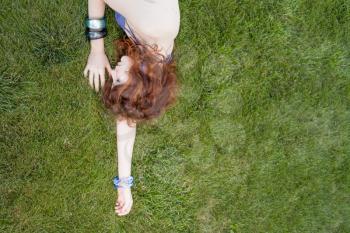 very  pretty red headed women laying on the fresh green grass and enjoy summertime