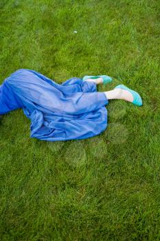 womens legs in the fresh grass part of the body shot, blue skirt