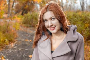 foxy-red haired women outdoors weared jacket at autumn time. Smiling and enjoy autumn air