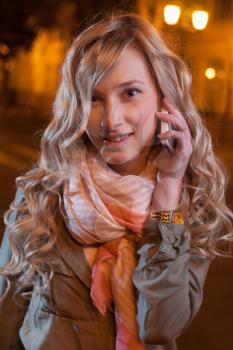 long haired 20s women outdoor in evening. She looking at camera and use mobile phone