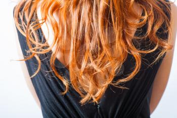 rear closeup view of the shoulders of red haired (carrot-top) female weared black dress