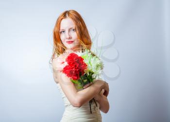 Horizontal image of redhead with bunch of flowers in studio on white. She looking at camera