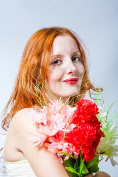 redhead with bunch of flowers in studio on white, side view