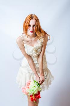 redhead with bunch of flowers in studio on white, looking at camera