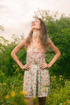 20s female enjoying summertime. Beautiful Young Woman standing in Meadow of Yellow Flowers.