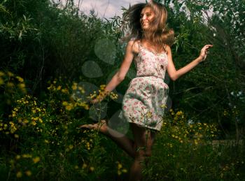 Cute female summertime dance. Happy girl dancing outdoors in grass and flowers