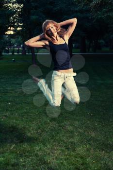 Summer fun. Girl in jeans jump on grass