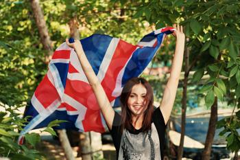 Brunette with britain flag in her hands outdoors in summer