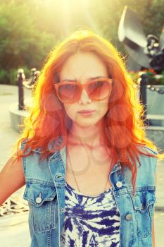 Casual red haired girl front view. Street fashion women in orange sunglasses backlit.