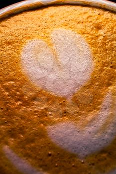 Heart shape froth art on top of cappuccino coffee macro image. Latte art classic macro.