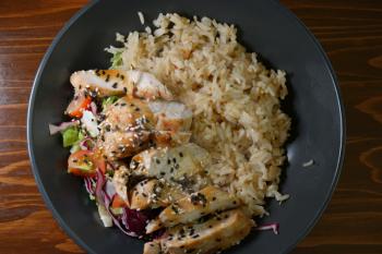 Spicy chicken on stir rice with salad and vegetables top view.