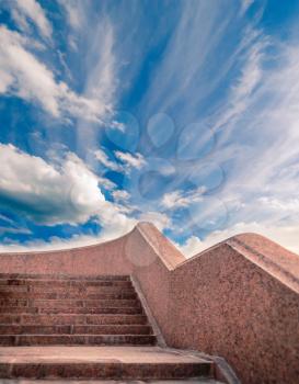 Granite stairway leaing up in fronbt of day sky with clouds, copyspace.