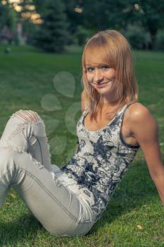 Sexy blond haired women sitting on green grass