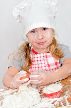 girl in chef's hat cooking dough for cake