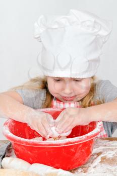 girl in chef's hat the breaks the egg in a bowl