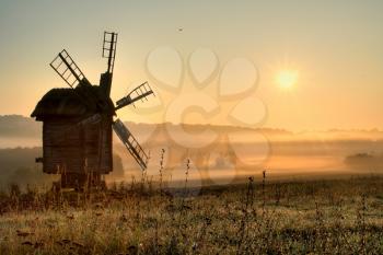 Royalty Free Photo of a Windmill in a Field at Sunrise