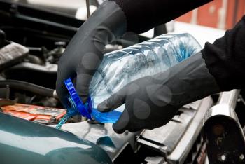 Royalty Free Photo of a Mechanic Filling a Car With Washing Liquid